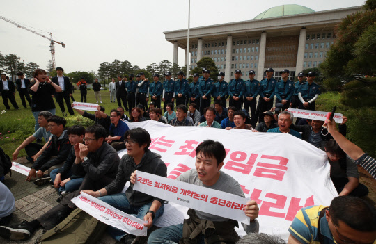 민주노총 조합원들이 지난 21일 오후 서울 여의도 국회에서 최저임금산입범위 확대 저지 총력투쟁을 위해 국회 경내에 진입해 연좌농성을 벌이며 구호를 외치고 있다. 연합뉴스